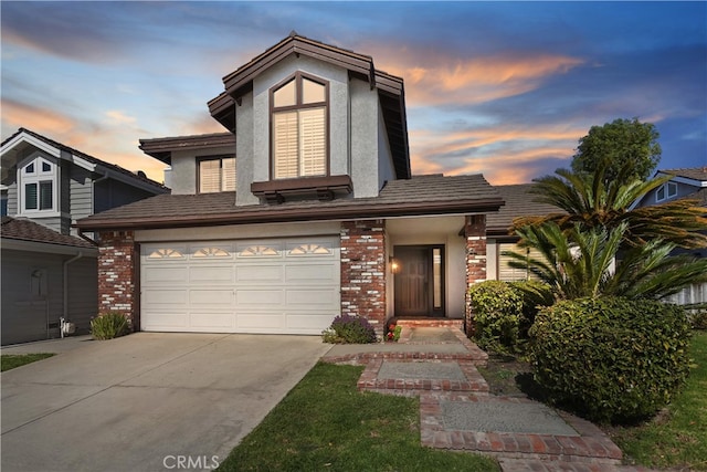 view of front of home featuring stucco siding, brick siding, and driveway