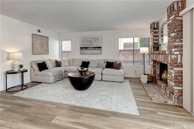 living area featuring a fireplace, wood finished floors, visible vents, and a wealth of natural light