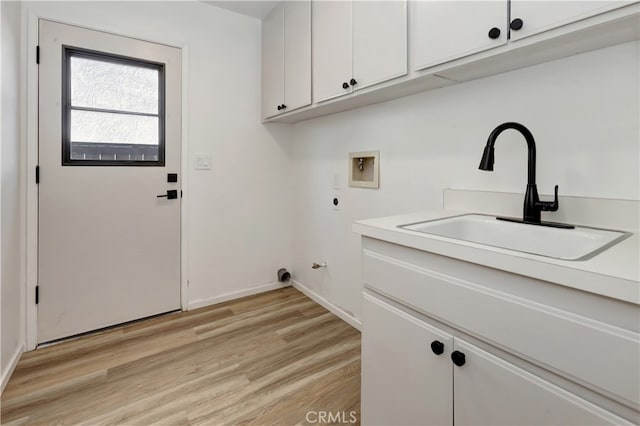 laundry area featuring hookup for a washing machine, light wood-style floors, cabinet space, hookup for an electric dryer, and a sink