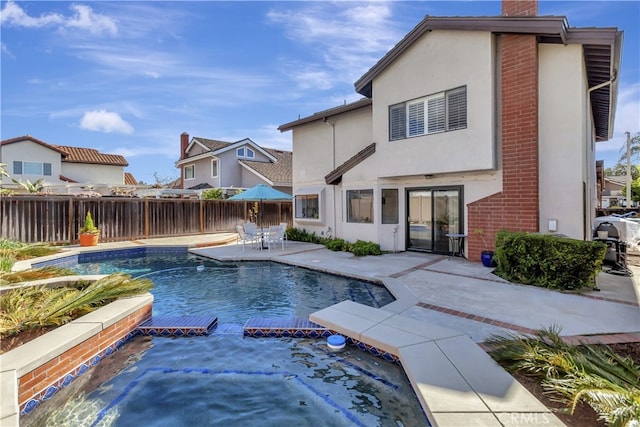 view of pool featuring fence, a pool with connected hot tub, and a patio area