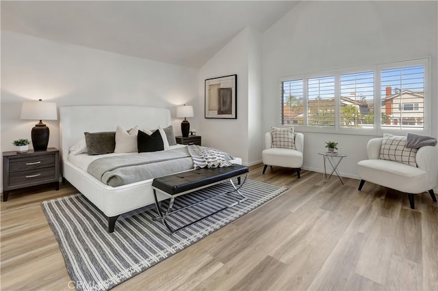 bedroom featuring light wood-style flooring, baseboards, and high vaulted ceiling