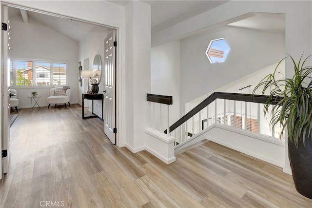 interior space with stairs, high vaulted ceiling, light wood-type flooring, and baseboards