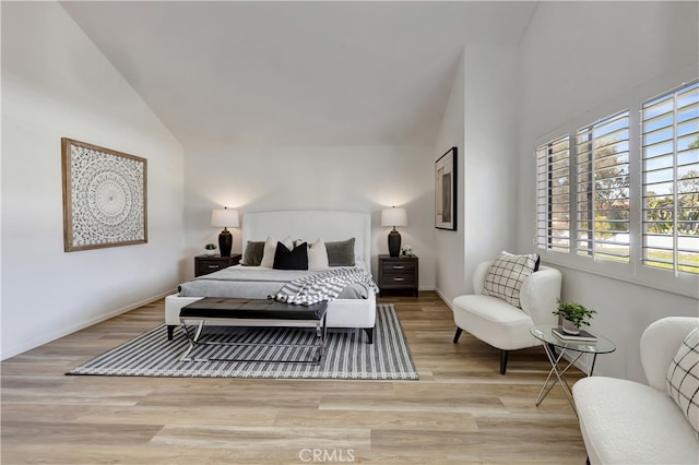 bedroom featuring baseboards, light wood-type flooring, and high vaulted ceiling