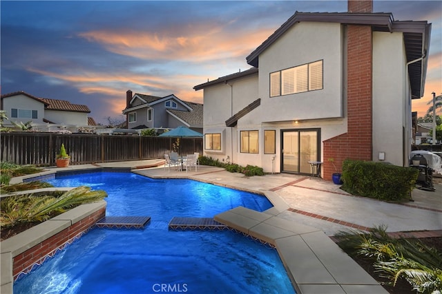 view of pool featuring a patio, a pool with connected hot tub, and fence