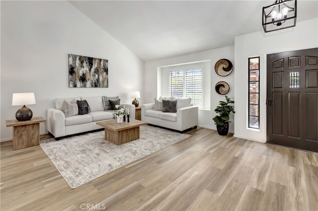 living area with light wood-type flooring, baseboards, high vaulted ceiling, and a chandelier