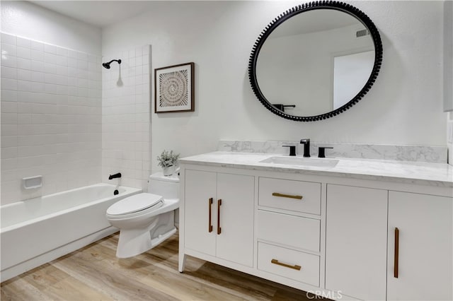 bathroom with visible vents, toilet, wood finished floors, washtub / shower combination, and vanity