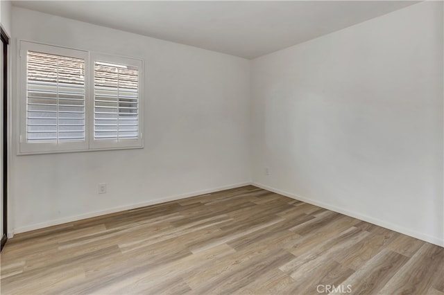 empty room featuring baseboards and light wood finished floors