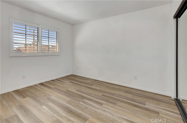 empty room featuring baseboards and light wood-style flooring