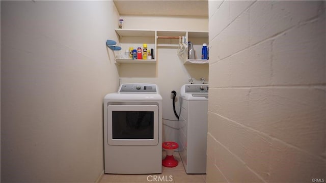 clothes washing area featuring concrete block wall, laundry area, and washer and clothes dryer