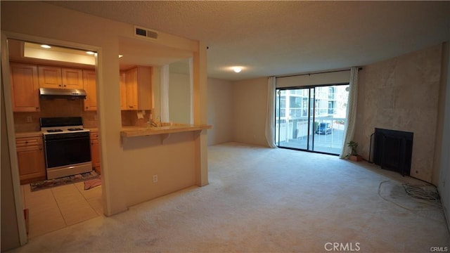 kitchen with light carpet, under cabinet range hood, visible vents, and white range with gas cooktop