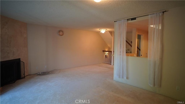 spare room with a large fireplace, carpet flooring, and a textured ceiling