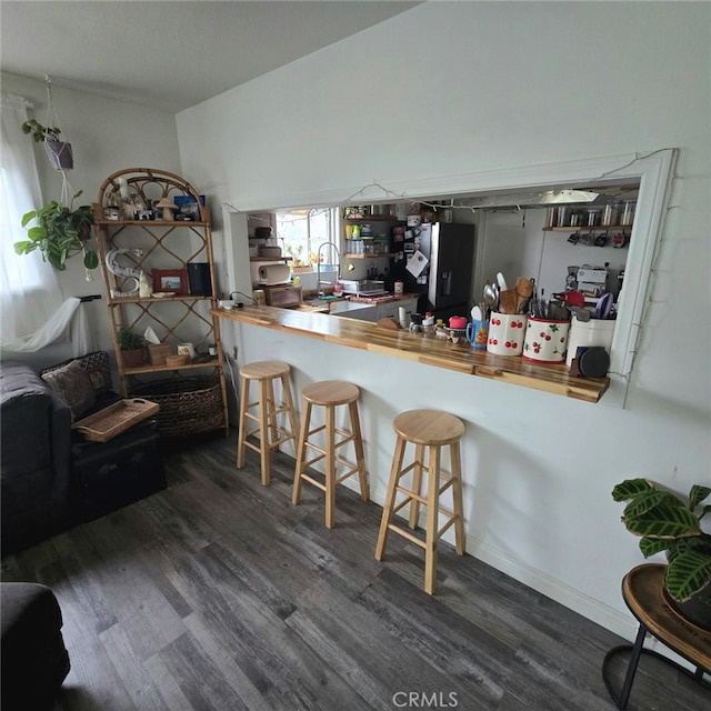 kitchen with wood finished floors, butcher block countertops, and black fridge with ice dispenser