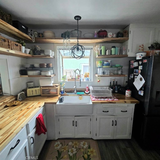 kitchen with wood counters, a sink, white cabinetry, freestanding refrigerator, and open shelves