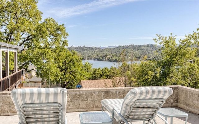 view of patio / terrace with a water view and a view of trees