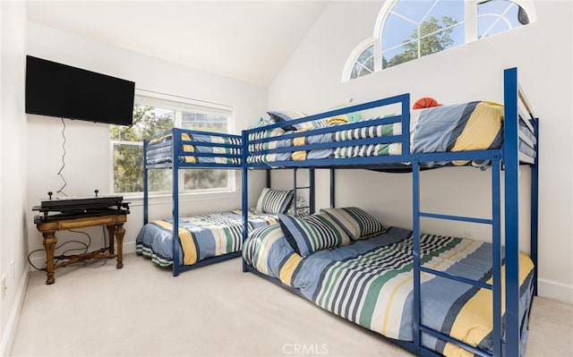 carpeted bedroom featuring high vaulted ceiling and baseboards