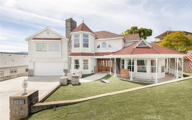 rear view of property with an attached garage, concrete driveway, a yard, stucco siding, and a chimney