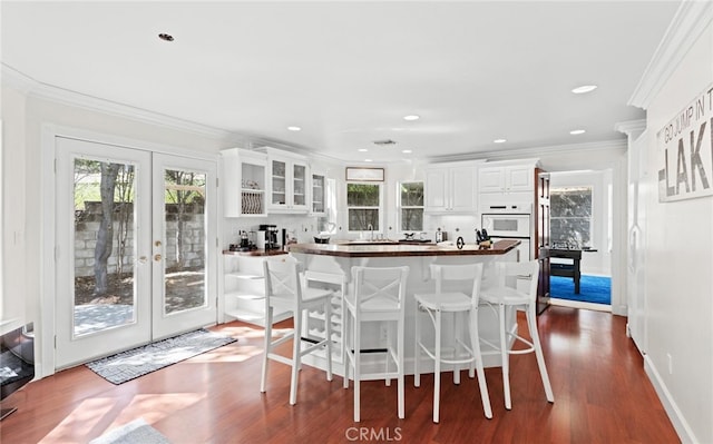 kitchen featuring ornamental molding, dark wood-style flooring, white cabinetry, and a healthy amount of sunlight