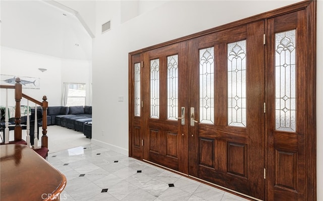 entryway featuring stairs, a towering ceiling, visible vents, and baseboards