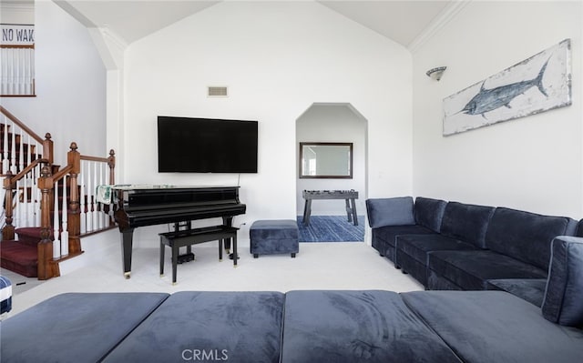 carpeted living room with arched walkways, crown molding, visible vents, high vaulted ceiling, and stairs