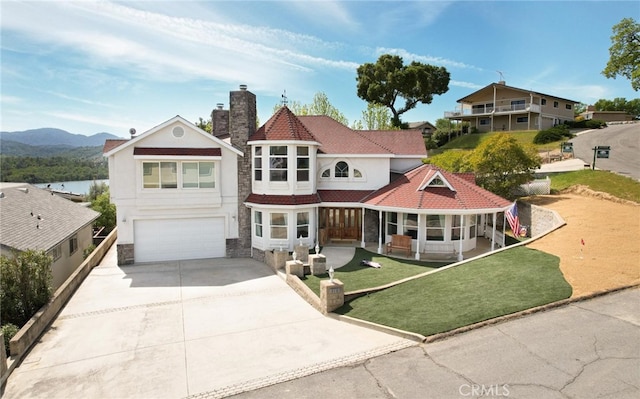 victorian home with driveway, a chimney, an attached garage, and stucco siding