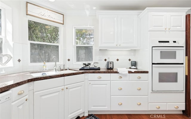 kitchen with white appliances, a sink, white cabinetry, ornamental molding, and backsplash