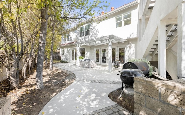 back of property with stairs, french doors, stucco siding, a pergola, and a patio area