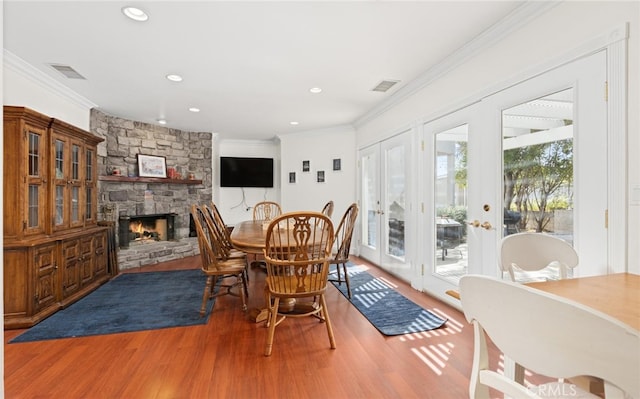 dining room featuring ornamental molding, a fireplace, wood finished floors, and visible vents