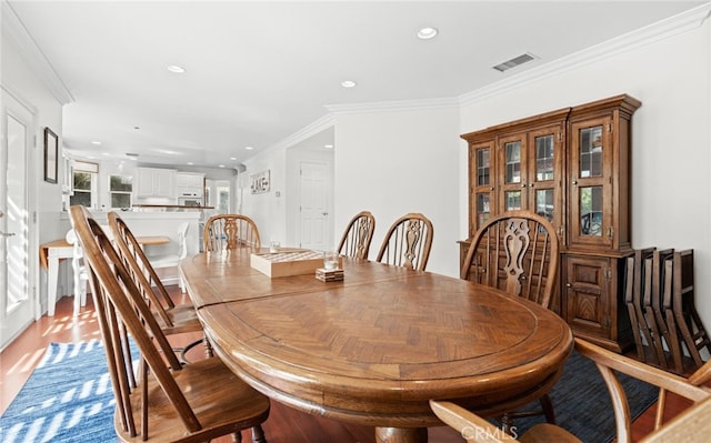 dining room with light wood-type flooring, visible vents, crown molding, and recessed lighting