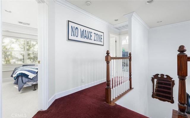 hallway featuring carpet floors, crown molding, visible vents, an upstairs landing, and baseboards