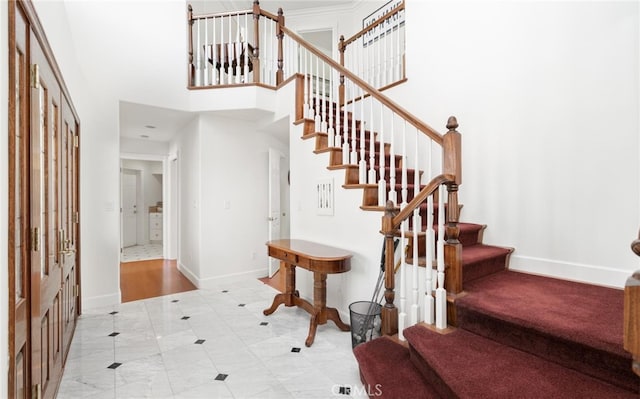 entrance foyer featuring stairway, a towering ceiling, and baseboards