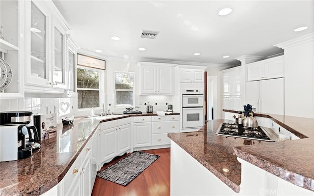 kitchen with white double oven, paneled built in refrigerator, crown molding, stainless steel gas stovetop, and a sink