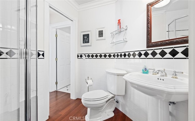 bathroom featuring toilet, a wainscoted wall, wood finished floors, tile walls, and crown molding