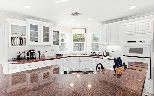 kitchen with white appliances, visible vents, crown molding, white cabinetry, and a sink