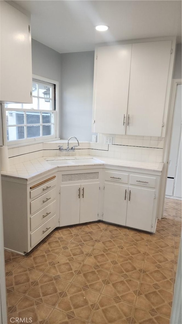 kitchen featuring recessed lighting, white cabinets, a sink, and decorative backsplash