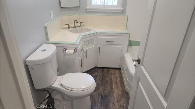 bathroom with decorative backsplash, toilet, wood finished floors, a bathtub, and vanity