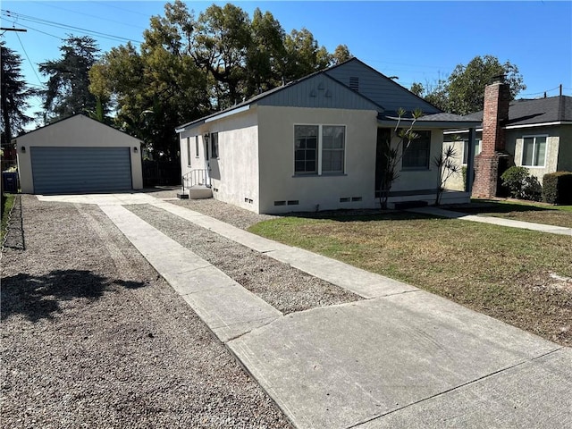 view of front of property with an outbuilding, a detached garage, crawl space, stucco siding, and a front lawn