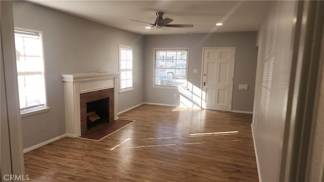 unfurnished living room with a fireplace, wood finished floors, a ceiling fan, and baseboards