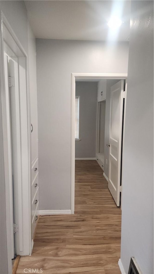 corridor featuring light wood-style floors, visible vents, and baseboards