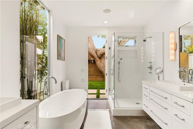 bathroom featuring concrete flooring, a stall shower, a freestanding bath, and vanity