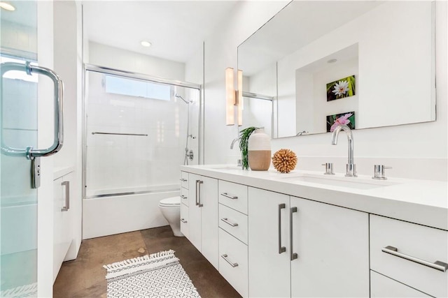 bathroom with double vanity, bath / shower combo with glass door, toilet, concrete flooring, and a sink