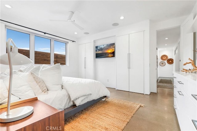 bedroom featuring concrete flooring, ceiling fan, recessed lighting, and multiple closets