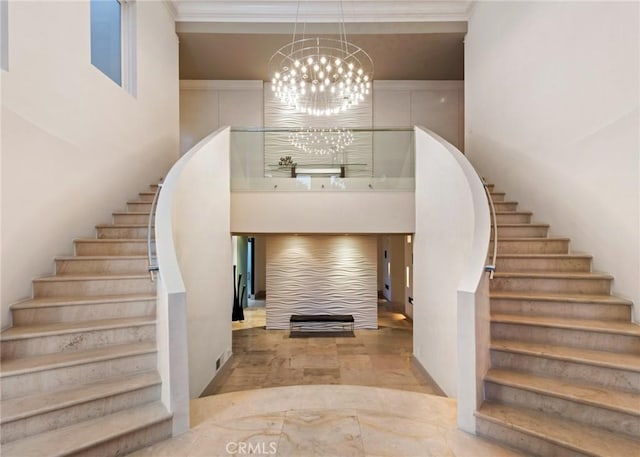 entrance foyer featuring a chandelier, crown molding, a towering ceiling, and stairs