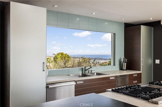 kitchen with recessed lighting, stainless steel appliances, a sink, light countertops, and backsplash