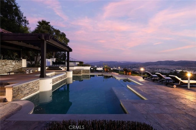 pool at dusk featuring a patio area and an outdoor pool