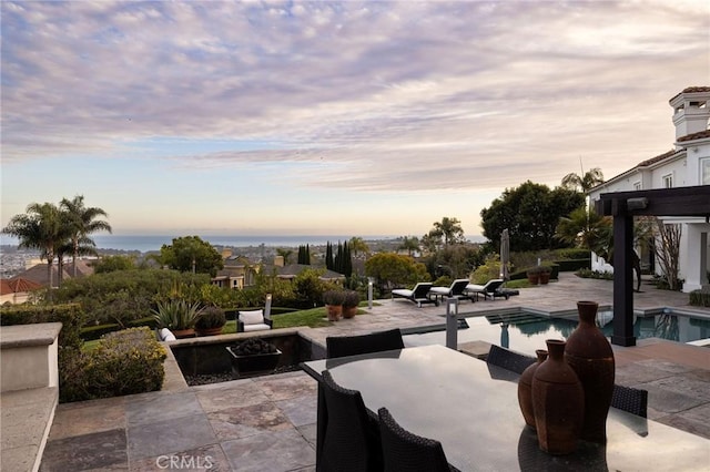 view of patio with an infinity pool, outdoor dining area, and a water view