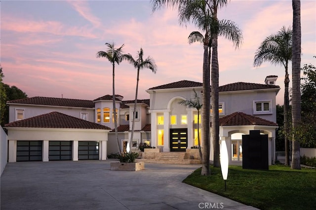 view of front of house featuring french doors, a tile roof, stucco siding, concrete driveway, and a garage