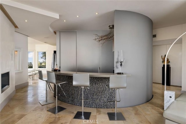 bar featuring recessed lighting, wet bar, and a glass covered fireplace