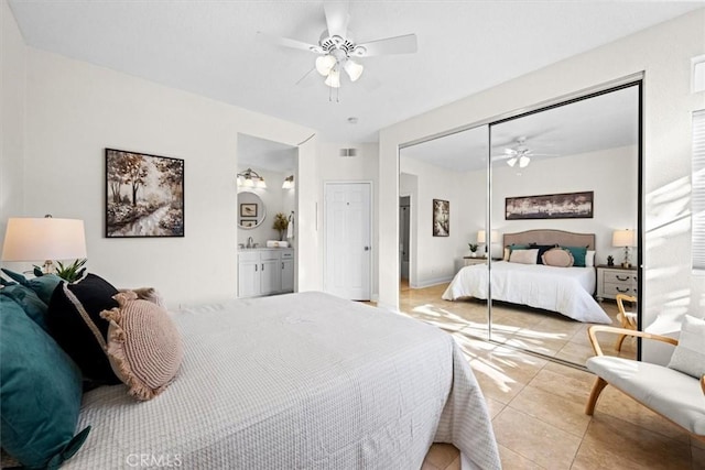 bedroom featuring light tile patterned floors, visible vents, ensuite bath, ceiling fan, and a closet