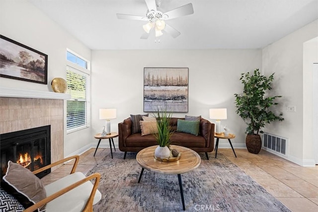 living room featuring a tiled fireplace, tile patterned flooring, visible vents, and baseboards