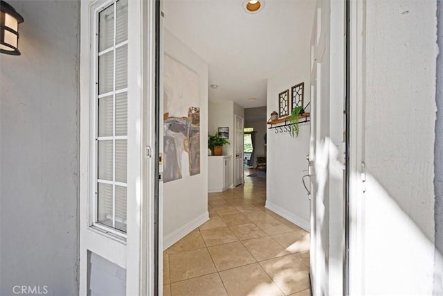 hallway featuring light tile patterned flooring and baseboards